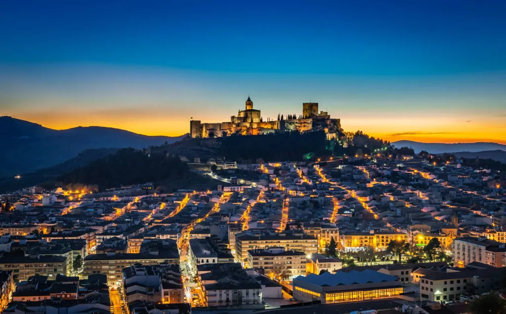 Alcalá la Real iluminada al anochecer, con la Fortaleza de la Mota en lo alto del cerro